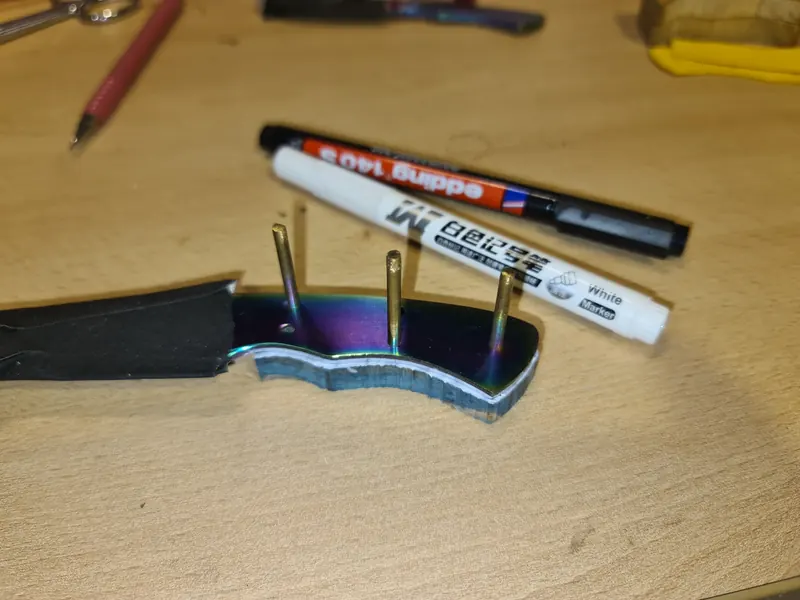 A coated-blade knife during handle assembly, with long pins still projecting