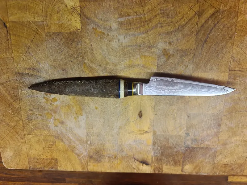 Slim patterned kitchen knife with a dark pointed handle and pale, blue and yellow spacer bands