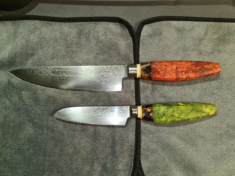 Finished kitchen knives with red and green handles laid together on a grey cloth
