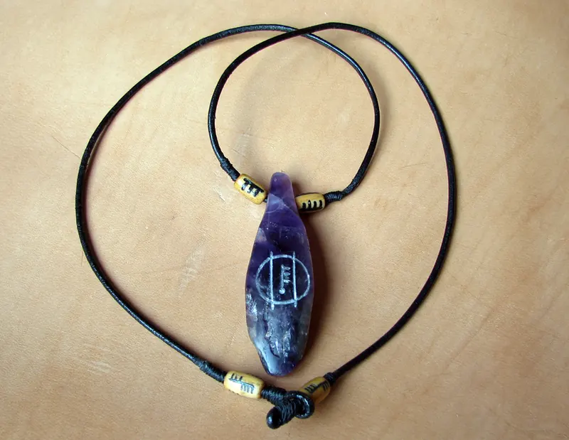 Dark polished pendant on a cord with small contrasting beads