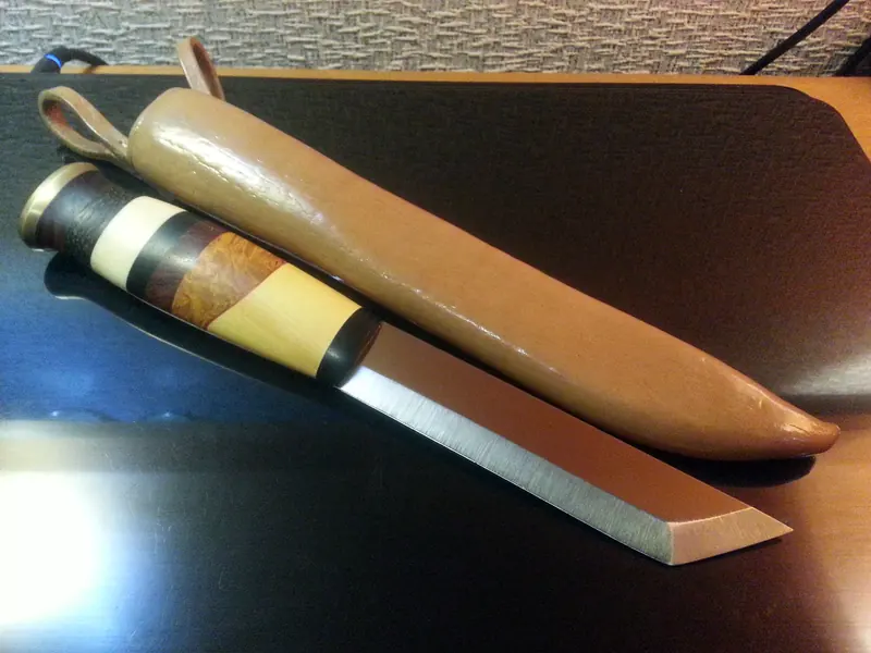 Straight-edged knife with a handle made of alternating light and dark sections beside a tan leather sheath
